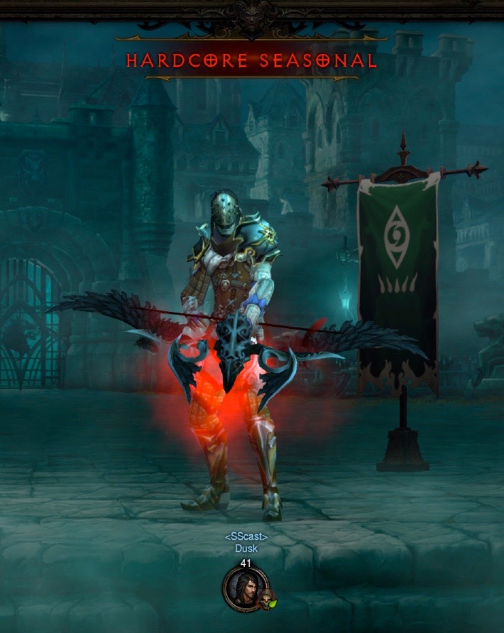 A Demon Hunter carries a large, feathered, crossbow. He is wearing a mix of reasonably tough armor. Next to him is a green banner with some symbols on it. Above his head it says "Hardcore Seasonal".