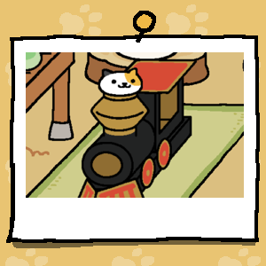 Sunny is a calico cat with a mostly white face, one black ear, and a large orange spot covering a big part of their face. Sunny is looking out of the cardboard train's smokestack.
