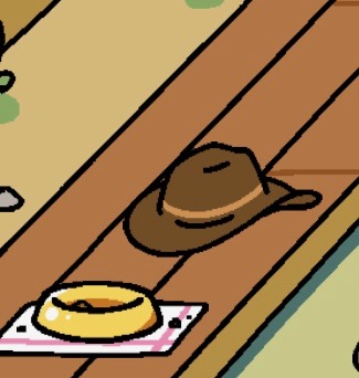A large brown cowboy hat is on the floor next to an empty food dish that is sitting on a white towel with pink stripes.