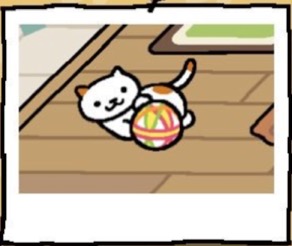 A white cat with a few brown spots plays with a ball that is made of fabric.