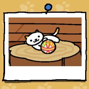 A white cat with one black ear and one yellow ear has a yellow spot at the end of their tail. They are playing with a fabric ball.