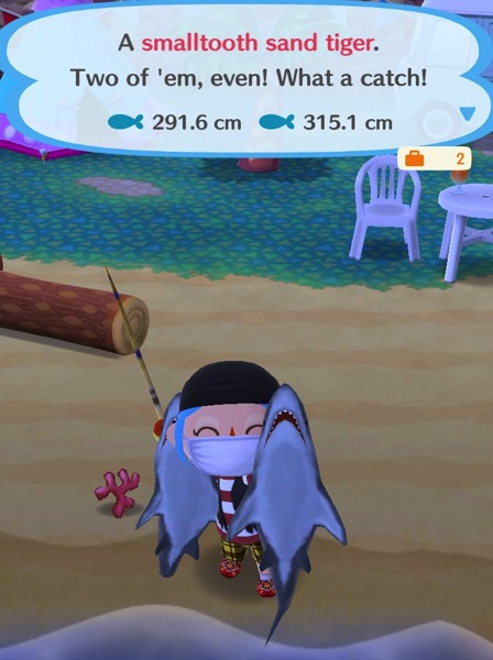 My Pocket Camp character holds up two smalltooth sand tigers.