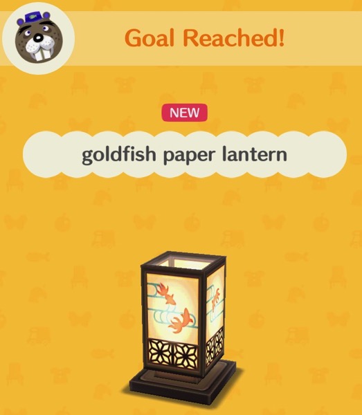 A rectangular paper lantern is decorated with silhouettes of goldfish that are swimming in water (represented by lines). The base of the lantern, and its corners, are made of wood.