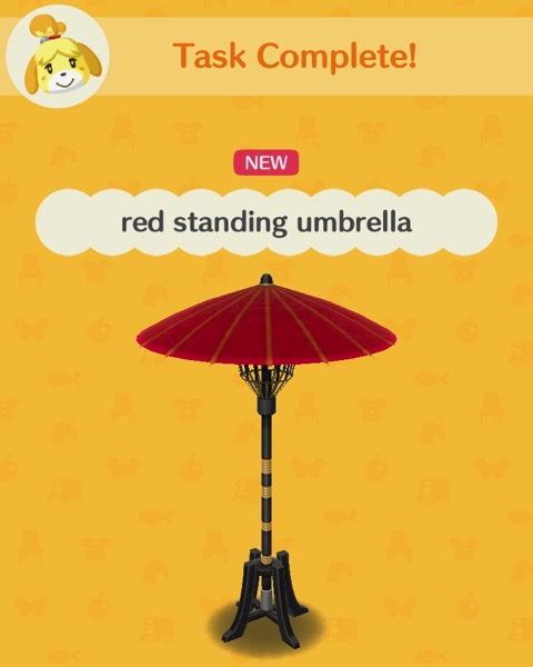 A tall umbrella with a red top is supported by four legs that the end of the umbrella has been placed into.