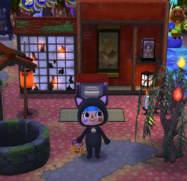 My Pocket Camp character wears a cat Halloween costume. They stand near the collection of Haunted Scavenger Hunt items.