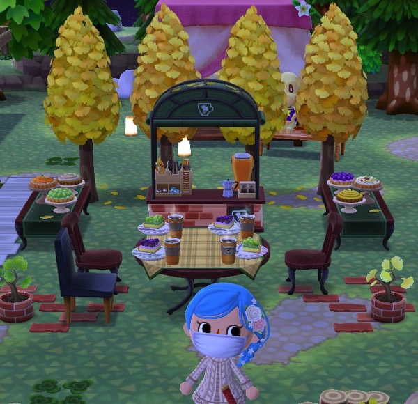 My Pocket Camp character stands in front of a cafe (which is missing a chair). The ginko cafe coffee stand has been added.