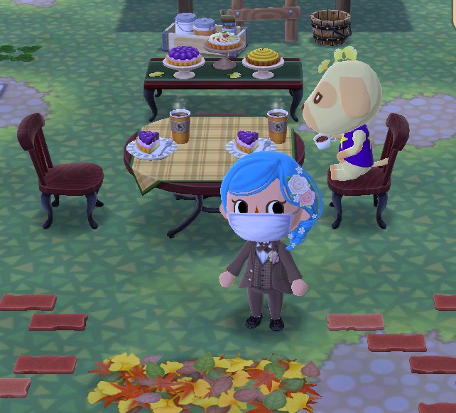 My Pocket Camp character is wearing a brown tuxedo and a blue wig that has flowers in it. Behind them is a cafe table with a tablecloth and two sets of plum dessert coffee set. The berry fall dessert set is beyond that.