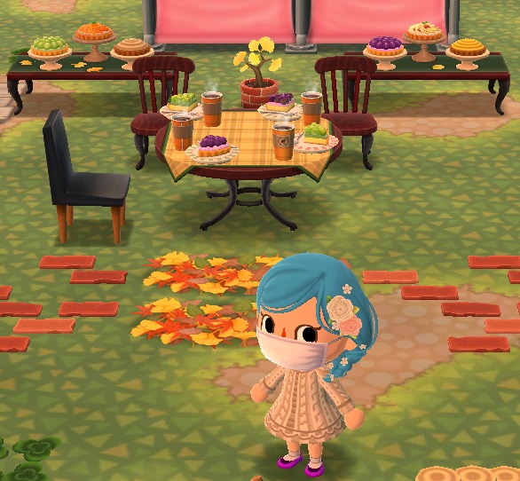 My Pocket Camp character stands in front of a cafe table with deserts on it. Behind the chairs are two tables with more desserts on them.