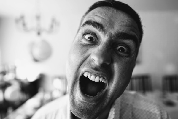 Black and white photo of a man who is making an angry face. Photo by Dmitry Vechorko on Unsplash