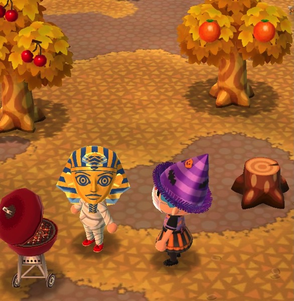 My Pocket Camp character is wearing a purple fright-night hat and the trick-or-treat dress (which looks like one of those plastic Halloween costumes kids buy from stores. Next to her is a player who is wearing a helmet that makes them look like King Tut. They are also wearing the mummy shirt and mummy pants. And red shoes, for some reason.