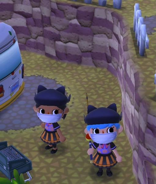 My Pocket Camp character is wearing the trick-or-treat dress. They are also wears a black beanie with cat ears, black tights, and black shoes. They are also wearing a white mask. The player next to her is also wearing the trick or treat dress, the black cat ears beanie, and black shoes (but slightly different leggings. The other player also wears a white mask. 