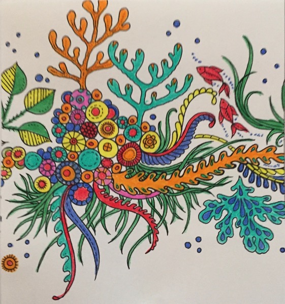 A somewhat blurry coloring sheet features an undersea scene. There are two red fish swimming around a collection of circular creatures that are in a group. There are leaves and vines that are growing out of the circular creatures.