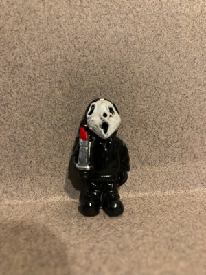 Day sixteen gave me Ghost Face (from the Scream movies). This hard plastic figure is wearing black clothing. He holds a knife that has blood on it. His mask looks like the Ghost Face in the movies.
