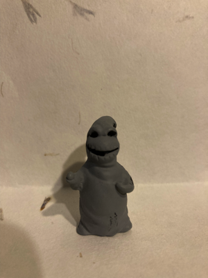 A grey plastic figure that looks a lot like Oogie Boogie from Nightmare Before Christmas.