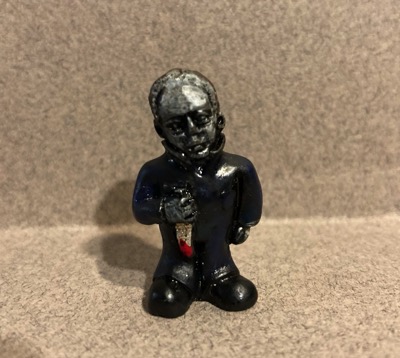 A small, plastic figure that appear to be someone's idea of Frankenstein. The figure carries a bloody sword in one hand.