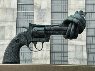Photo of a statue of an oversized handgun with a knot tied at the end of it by Maria Lysenko on Unsplash