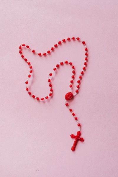 A rosary made of red plastic beads and a red plastic cross by Karolina Grabwska on Pexels.