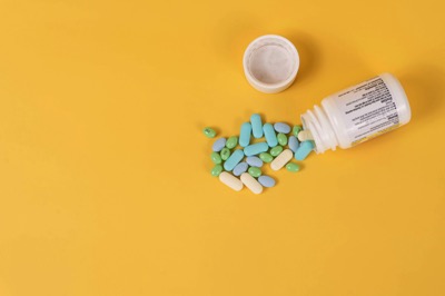 a bottle of a variety of pills spilled out of a white bottle with the cap off by Etactics Inc.